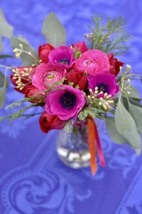 A wedding table centrepiece posy with colourful anemones, ranunculus and bright ribbons. By Tuckshop Flowers, Birmingham. Contact me to discuss wedding flowers.