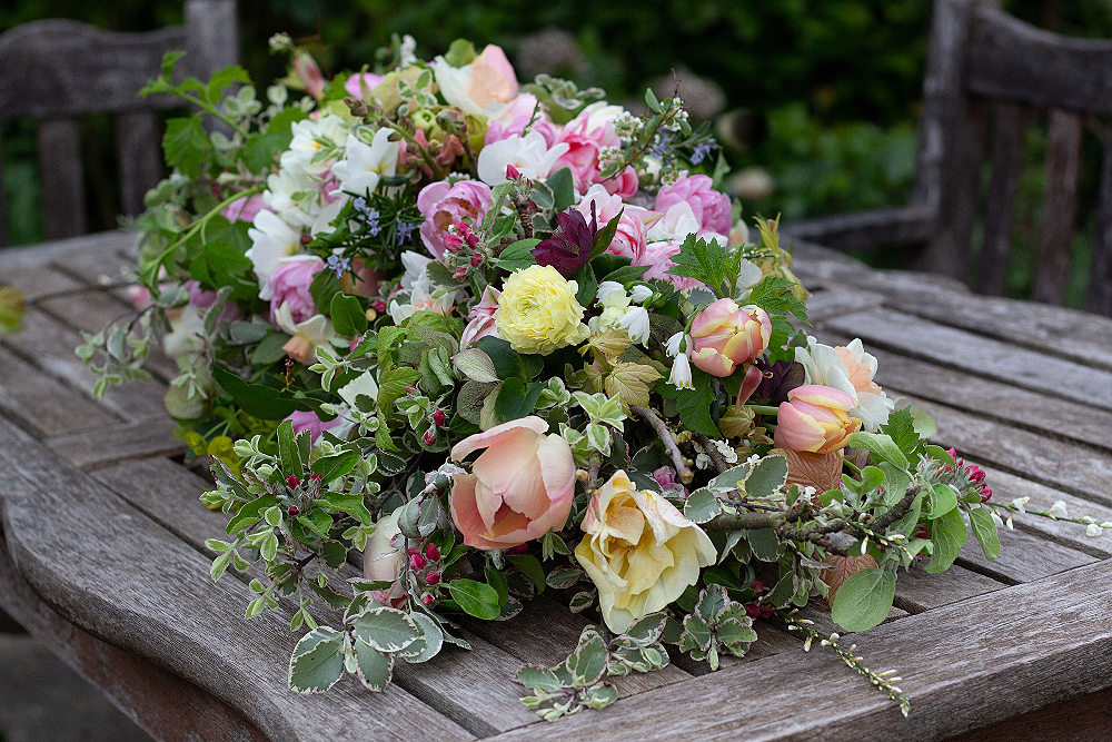 An eco-friendly funeral casket spray made with locally grown flowers features peach, lemon and pink tulips mixed with scented rosemary, pink apple blossom and delicate foliage. Tuckshop Flowers Birmingham.